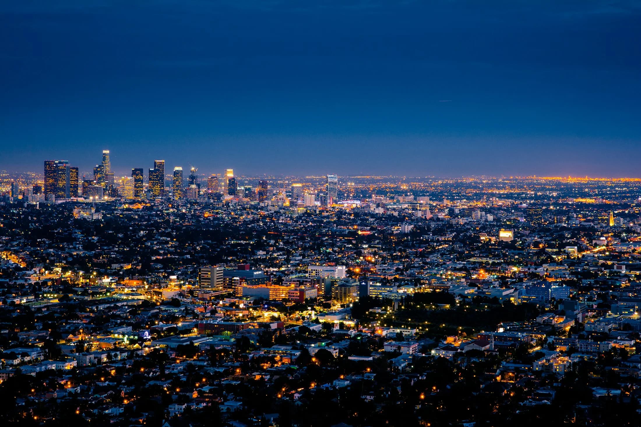 Downtown Los Angeles skyline and surrounding city lights at blue hour.