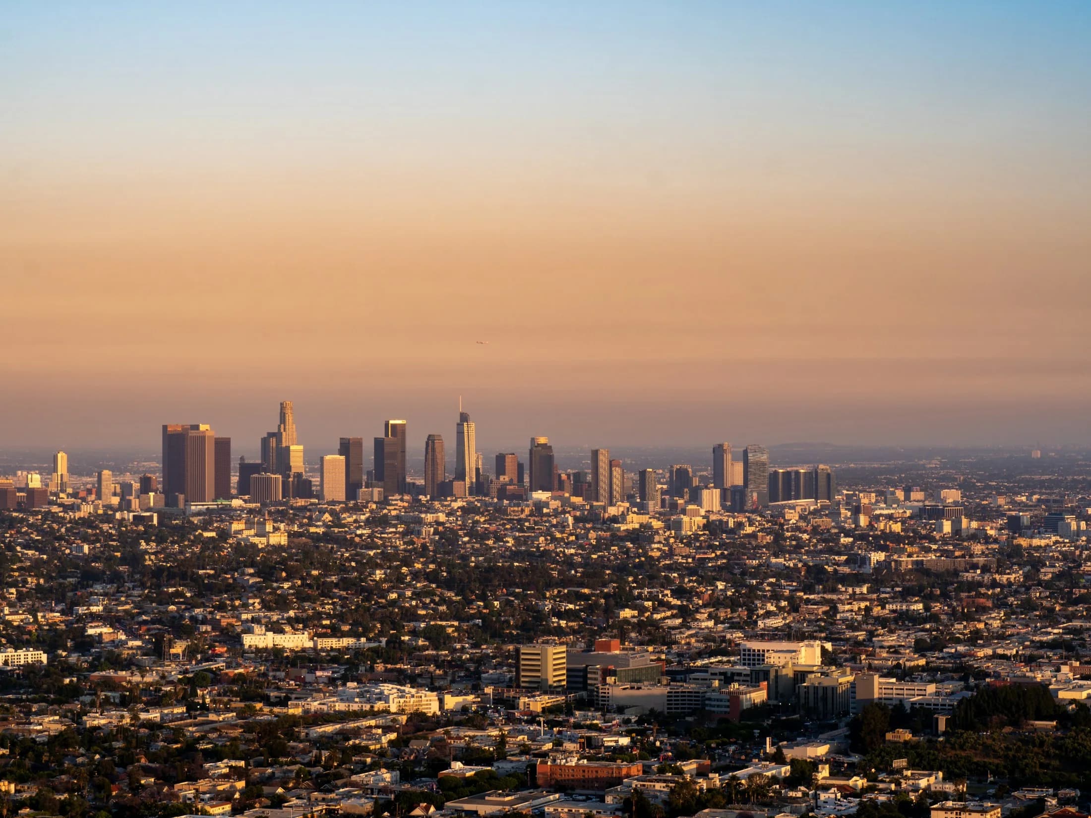 Los Angeles skyline and surrounding neighborhoods in warm evening light, viewed from Griffith Observatory.