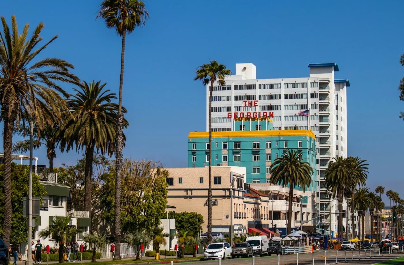 Palm trees line Ocean Avenue beside the turquoise Georgian Hotel in Santa Monica.